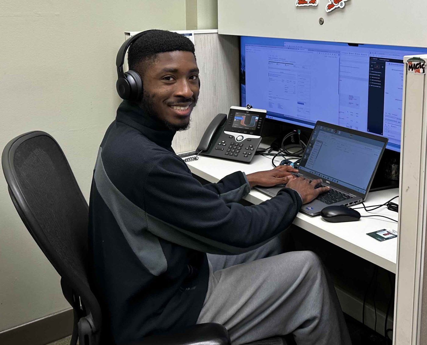Billy working at a desk with a laptop and a monitor